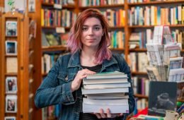 A woman holding a stack of books in the independent San Francisco bookstore where she works.